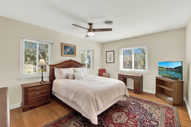 bedroom with hardwood / wood-style flooring, ceiling fan, and multiple windows