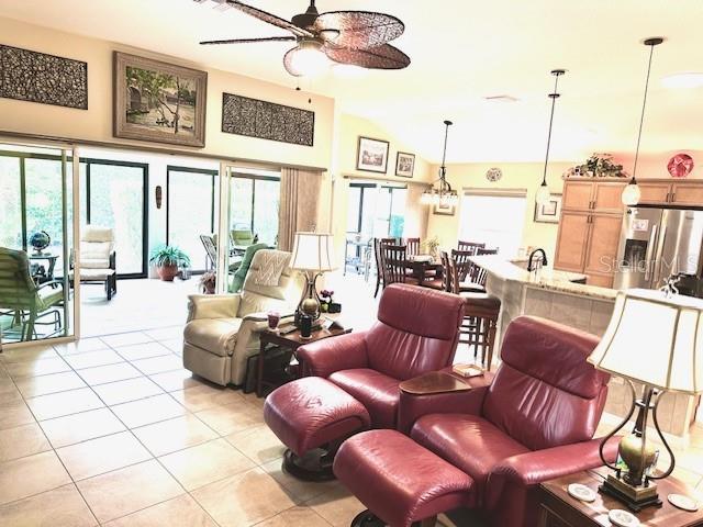 tiled living room with ceiling fan and vaulted ceiling