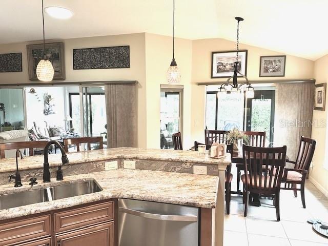 kitchen featuring vaulted ceiling, sink, light tile patterned floors, dishwasher, and hanging light fixtures