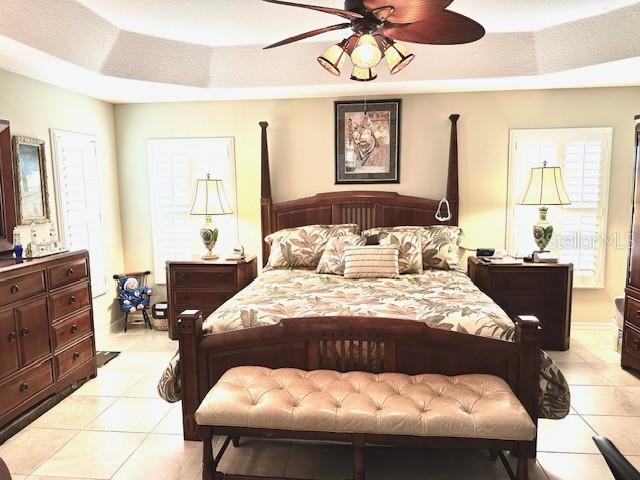 bedroom featuring light tile patterned floors, a raised ceiling, and ceiling fan