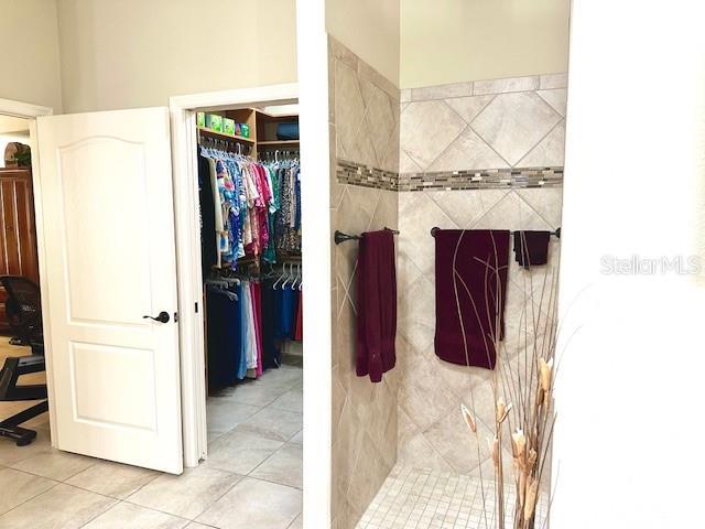 bathroom with a tile shower and tile patterned flooring