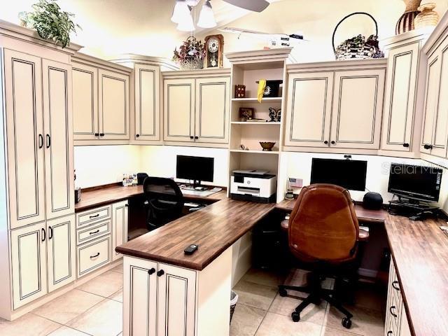 office space with ceiling fan, built in desk, and light tile patterned floors