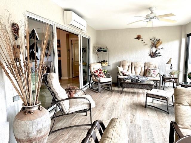 interior space with ceiling fan, wood-type flooring, and a wall unit AC