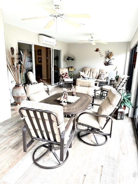 interior space featuring ceiling fan, wood-type flooring, and a wall mounted air conditioner