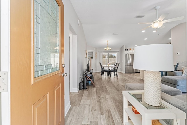 entrance foyer with vaulted ceiling, light hardwood / wood-style floors, and ceiling fan with notable chandelier