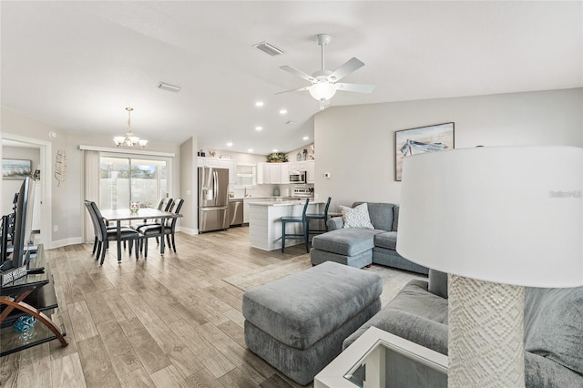 living room featuring ceiling fan with notable chandelier, light hardwood / wood-style floors, and lofted ceiling