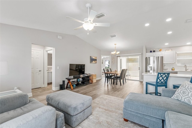 living room featuring ceiling fan with notable chandelier, light hardwood / wood-style flooring, lofted ceiling, and sink