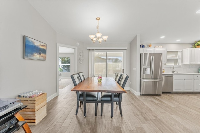 dining area featuring light wood-type flooring, sink, and an inviting chandelier