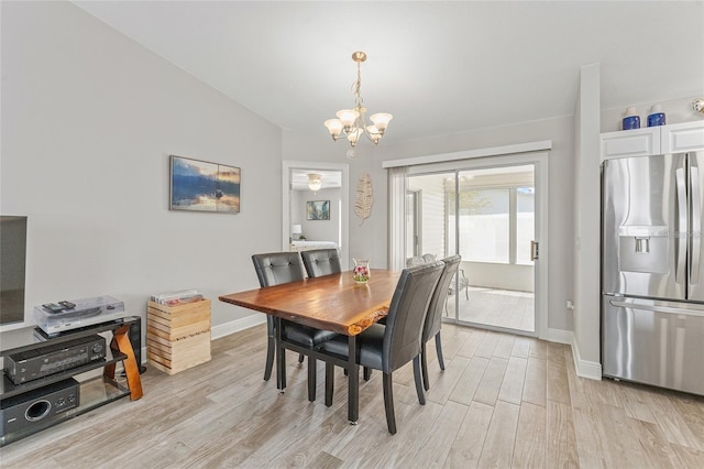 dining area featuring a notable chandelier, light wood-type flooring, and lofted ceiling