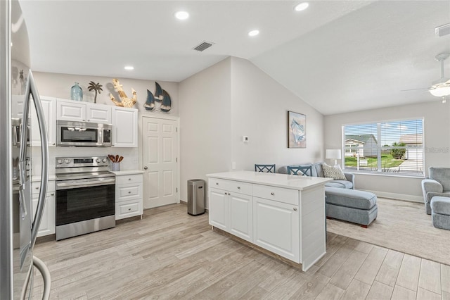 kitchen with ceiling fan, appliances with stainless steel finishes, lofted ceiling, white cabinets, and light wood-type flooring