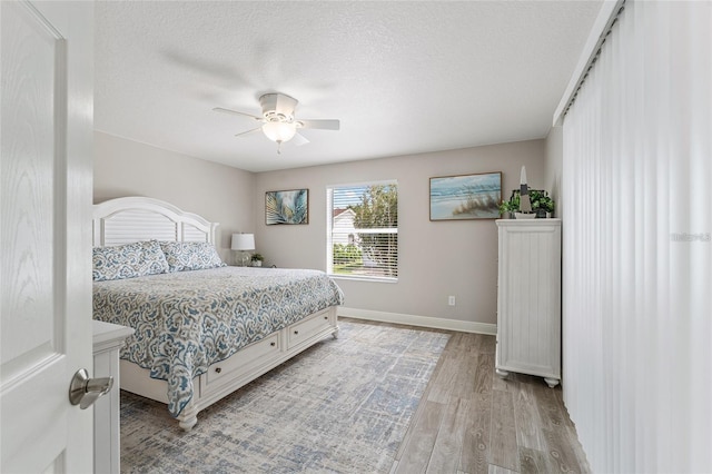 bedroom with ceiling fan, a textured ceiling, and light wood-type flooring