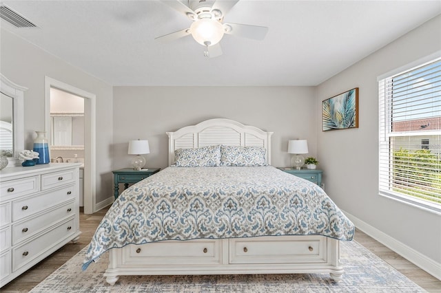 bedroom featuring light hardwood / wood-style floors, ensuite bath, and ceiling fan