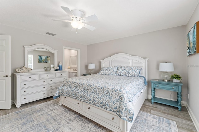 bedroom with light wood-type flooring, ensuite bath, and ceiling fan