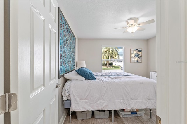 bedroom with hardwood / wood-style flooring, ceiling fan, and a textured ceiling