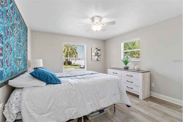 bedroom with ceiling fan, light hardwood / wood-style floors, and a textured ceiling