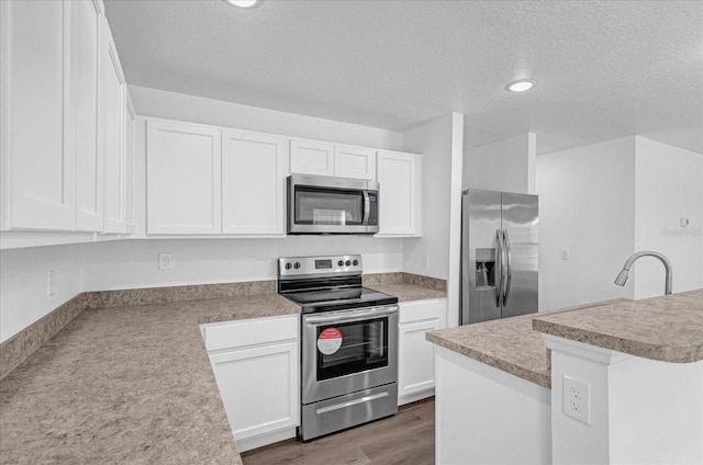 kitchen with white cabinetry, appliances with stainless steel finishes, dark wood-type flooring, and a textured ceiling