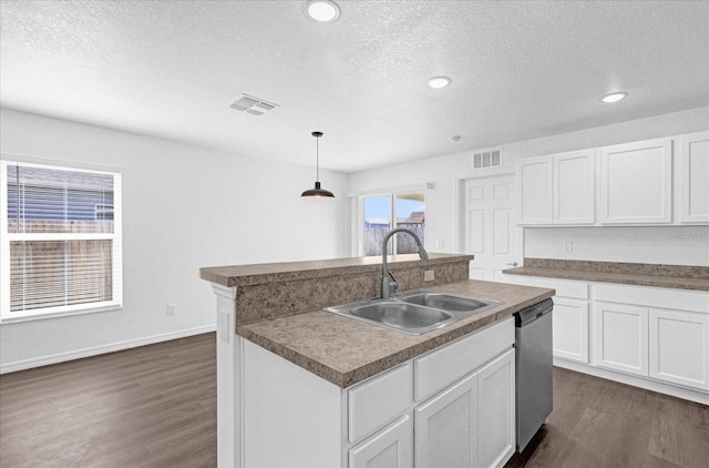 kitchen with pendant lighting, sink, white cabinets, stainless steel dishwasher, and a center island with sink