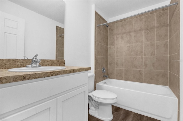 full bathroom with tiled shower / bath, hardwood / wood-style floors, vanity, and toilet