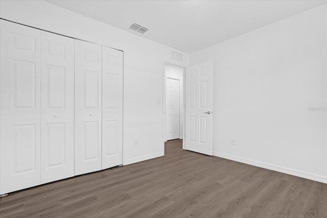 unfurnished bedroom with dark hardwood / wood-style flooring and a closet