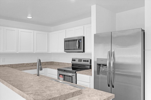 kitchen with stainless steel appliances, white cabinets, and kitchen peninsula