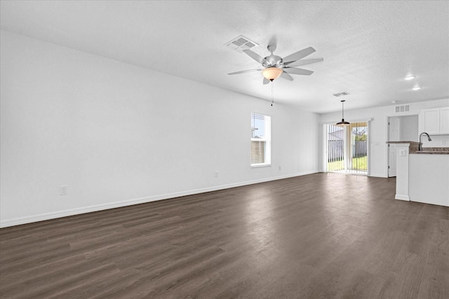 unfurnished living room featuring ceiling fan, dark hardwood / wood-style floors, and a textured ceiling