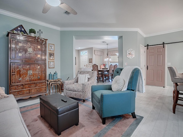 living room featuring hardwood / wood-style floors, ceiling fan with notable chandelier, a barn door, and ornamental molding