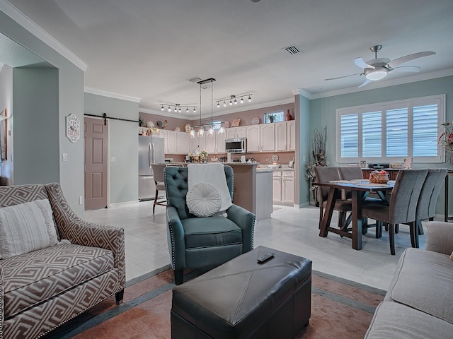 living room with rail lighting, ornamental molding, ceiling fan, a barn door, and light hardwood / wood-style floors