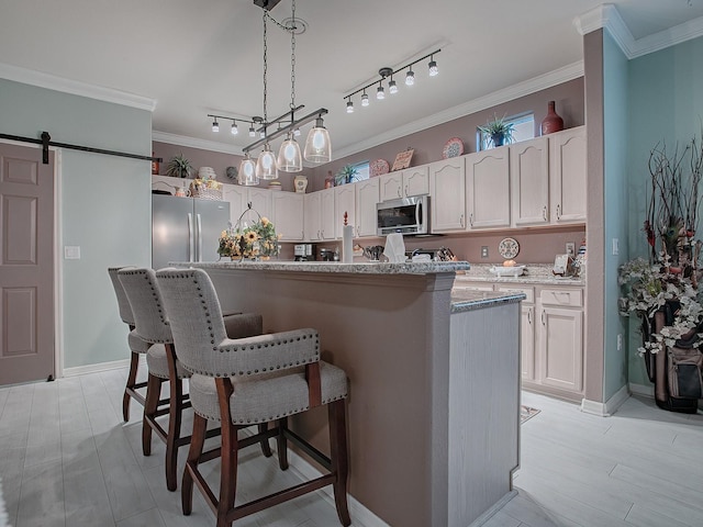 kitchen with pendant lighting, a barn door, a kitchen island, white cabinetry, and stainless steel appliances