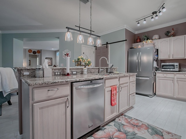 kitchen featuring a barn door, stainless steel appliances, hanging light fixtures, and crown molding