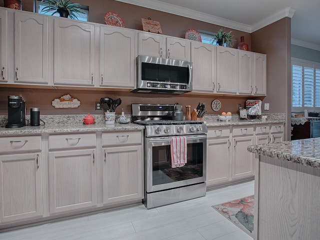 kitchen featuring light stone countertops, appliances with stainless steel finishes, white cabinetry, and crown molding