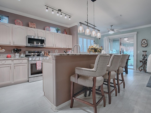 kitchen featuring a center island, white cabinets, hanging light fixtures, ornamental molding, and appliances with stainless steel finishes