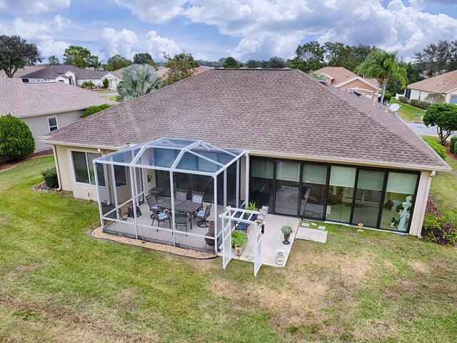 back of house featuring a patio, glass enclosure, and a lawn