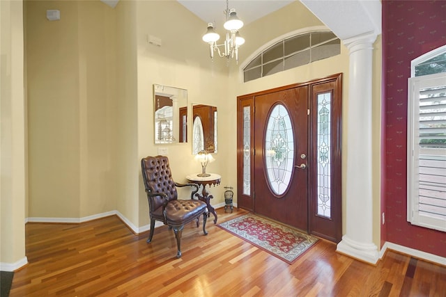 entryway featuring a chandelier, hardwood / wood-style floors, a towering ceiling, and decorative columns