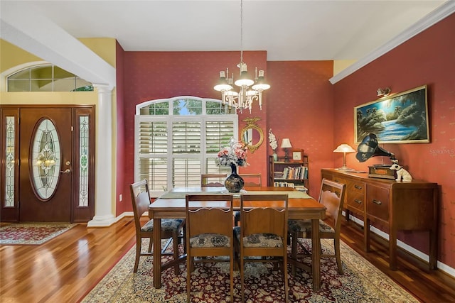 dining room featuring wood-type flooring, an inviting chandelier, and ornate columns