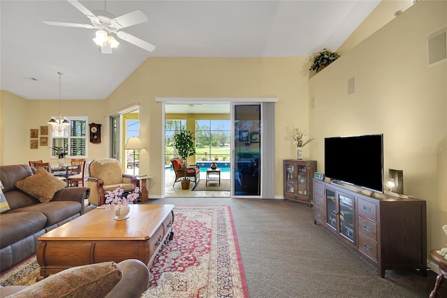 carpeted living room featuring ceiling fan with notable chandelier and vaulted ceiling