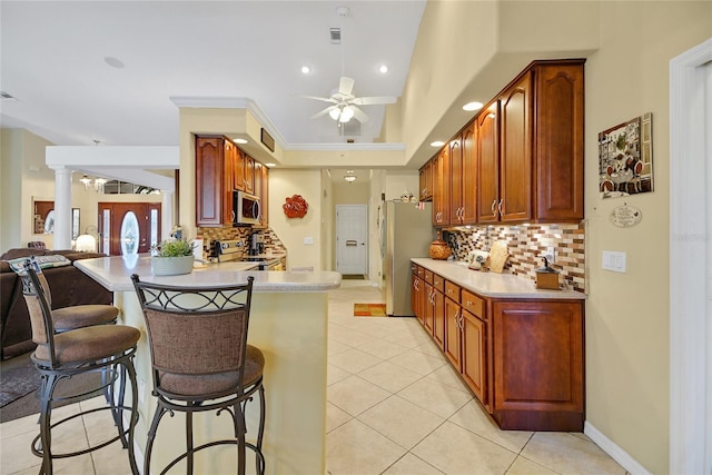 kitchen with ceiling fan, decorative backsplash, stainless steel appliances, and kitchen peninsula