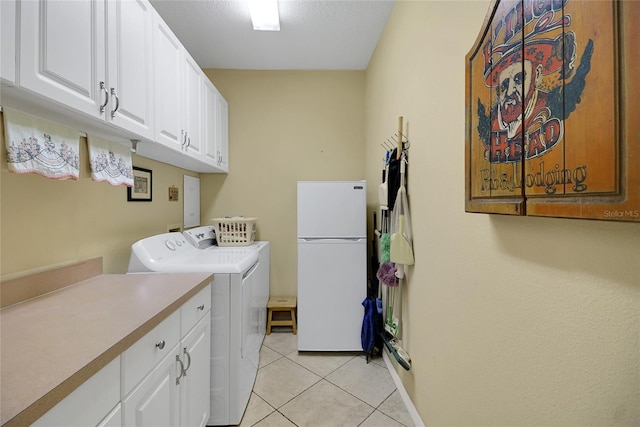 laundry room with washing machine and dryer, light tile patterned flooring, and cabinets