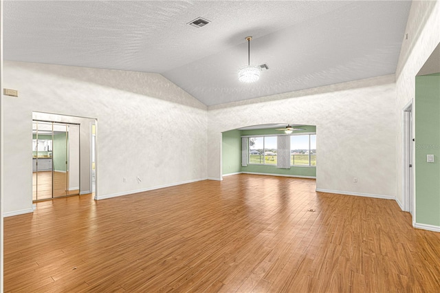 unfurnished living room with ceiling fan, hardwood / wood-style floors, high vaulted ceiling, and a textured ceiling