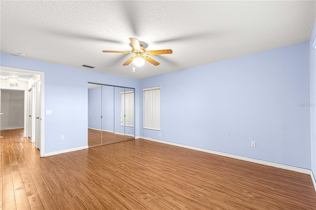 unfurnished bedroom featuring hardwood / wood-style flooring, ceiling fan, and a textured ceiling