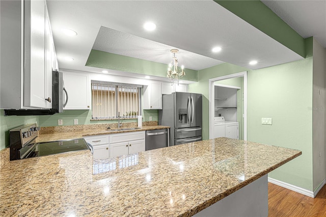 kitchen with white cabinetry, sink, kitchen peninsula, washer and dryer, and appliances with stainless steel finishes