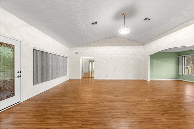 unfurnished living room with hardwood / wood-style flooring, a textured ceiling, and vaulted ceiling