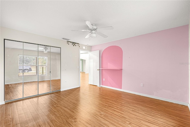 unfurnished bedroom with a textured ceiling, hardwood / wood-style flooring, a closet, and ceiling fan