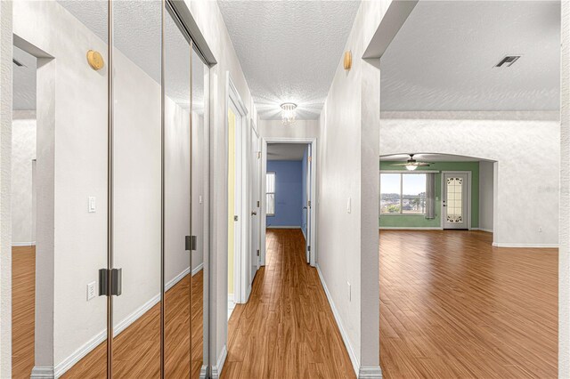 hall with wood-type flooring and a textured ceiling