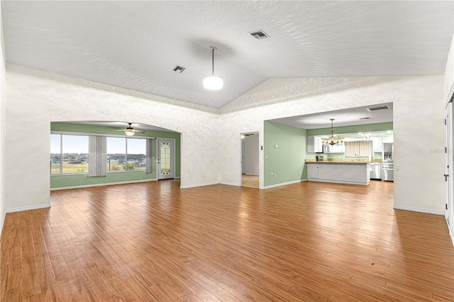 unfurnished living room with a textured ceiling, ceiling fan with notable chandelier, wood-type flooring, and lofted ceiling