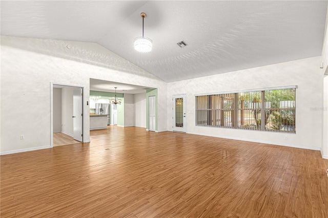 unfurnished living room with a chandelier, a textured ceiling, hardwood / wood-style flooring, and high vaulted ceiling