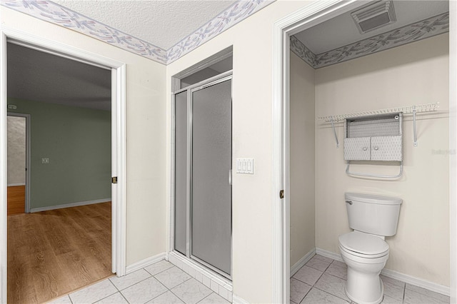 bathroom featuring a textured ceiling, toilet, an enclosed shower, and hardwood / wood-style flooring