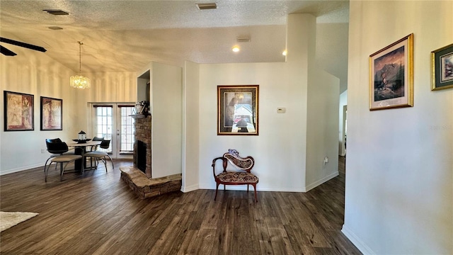 hall with a textured ceiling, high vaulted ceiling, an inviting chandelier, and dark wood-type flooring