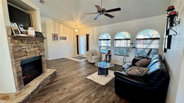 living room with a textured ceiling, vaulted ceiling, ceiling fan, dark wood-type flooring, and a fireplace