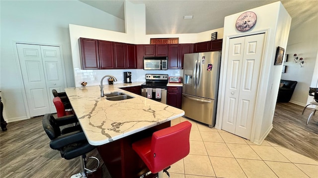 kitchen featuring a breakfast bar, sink, light hardwood / wood-style floors, kitchen peninsula, and stainless steel appliances