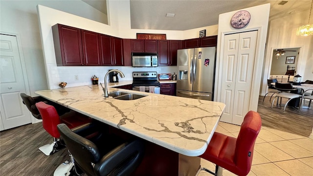 kitchen featuring a breakfast bar, sink, light hardwood / wood-style flooring, appliances with stainless steel finishes, and kitchen peninsula